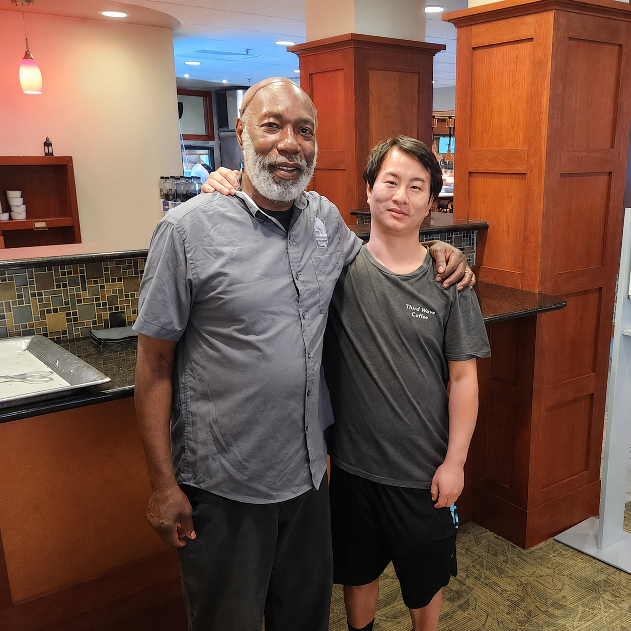 Josiah standing with a White Horse Village dining services employee during a visit.
