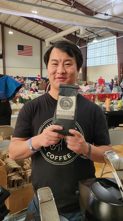 Josiah holding a bag of Third Horse Coffee at a community event